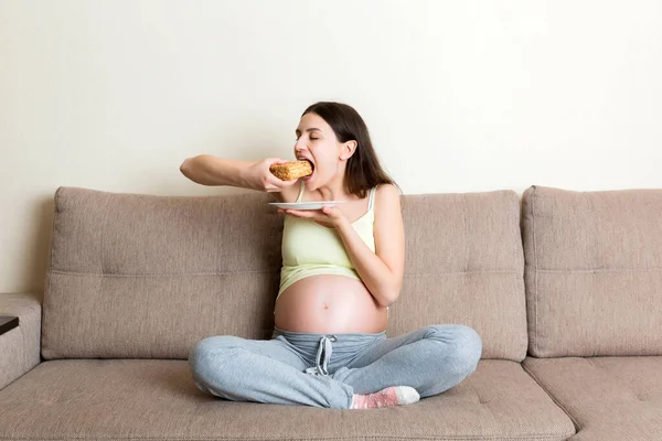 Mulher Grávida Animado Está Comendo Uma Fatia Bolo Descansando Sofá — Fotografia de Stock
