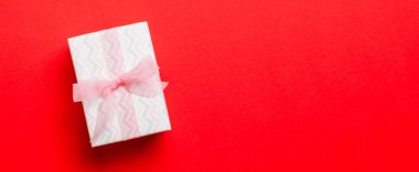 Üst görünüm Noel hediyesi kutusu, üzerinde pembe fiyonk ve fotokopi alanı olan kırmızı arkaplan.