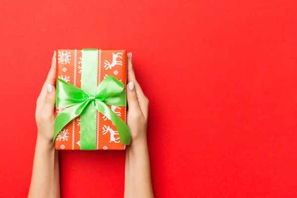 雌性手拿着带条纹的礼品盒 红色背景的彩带 圣诞概念或其他节日手工制作的礼品盒 概念顶视图与复制空间 — 图库照片