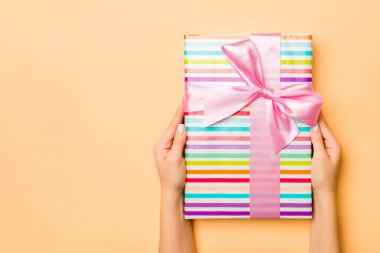 El ele tutuşmuş, hediye paketlenmiş ve altın kaplama arka planda fotokopi alanı ile süslenmiş bir kadın. Noel ve tatil konsepti.