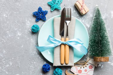 Çimento arka planında Noel yemeğinin bayram kompozisyonu. Tabakların üst görüntüsü, çatal bıçak ve şenlikli dekorasyonlar. Kopya alanı ile Yeni Yıl Uygulaması kavramı.