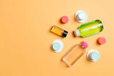 Renkli arka planda seyahat boyutunda kozmetik şişeler. Krema kavanozları düzdü. Vücut bakım stili kavramının en üst görünümü.