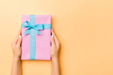 El ele tutuşmuş, hediye paketlenmiş ve altın kaplama arka planda fotokopi alanı ile süslenmiş bir kadın. Noel ve tatil konsepti.