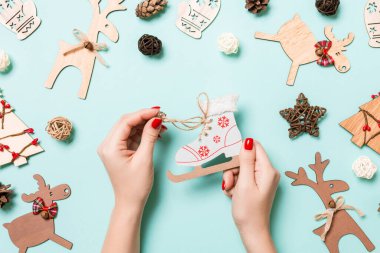 Mavi arka plandaki kadın ellerindeki patenlerin en üst görüntüsü. Noel süsleri. Yeni yıl tatili konsepti.