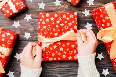 Kadın eli görüntüsü, yeni yılı şenlikli ahşap arka planda kutluyor. Hediye kutuları ve kar taneleri. Noel zamanı konsepti.