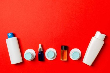 Yüz bakımı için en iyi bakış açısı: şişeler ve kavanozlar dolusu tonik, su, krem, renkli arka planda pamuk pedleri. Fikirleriniz için boş midye içeren vücut bakım konsepti.