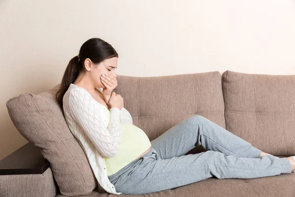 Pregnancy Morning Sickness. Pregnant Woman Having Nausea Feeling Bad in Sofa at the Home.