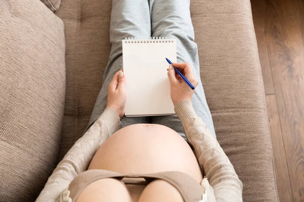 Hamile kadın notlar alır. Hamilelik, sağlık, tıp kavramı. Anne evde bebek bekliyor..