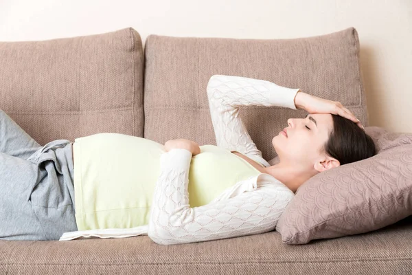 妊娠中の女性とともに痛みました腹上のソファに家 — ストック写真