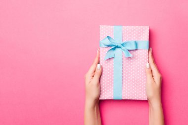 Kız Eller, hediye paketi taşıyor. Pembe arka planda Noel veya diğer bayramlarda hediye olarak. Fotokopi makaralı üst görünüm..