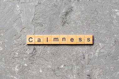 Tahta blokta sakinlik kelimesi yazılı. Çimento masasındaki sakinlik metni desing, konsept için.