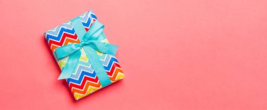 Yaşayan mercan arka planında mavi kurdeleli kağıda sarılmış Noel veya diğer tatil hediyeleri. Şimdiki kutu, renkli tabloda hediye süslemesi, kopya alanı ile üst görünüm.