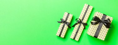 Noel 'de ya da yeni yılda siyah kurdeleli hediye kutusu yeşil arka planda, üst görünümde..