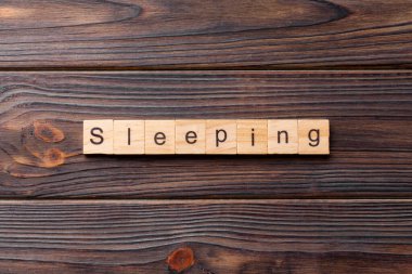 Tahta blokta uyku kelimesi yazıyor. Deksing, konsept için çimento masanın üzerinde uyuyan metin.