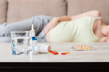 Çekici hasta hamile kadın kanepede yatıyor. Soğuk algınlığından hap alıyor..