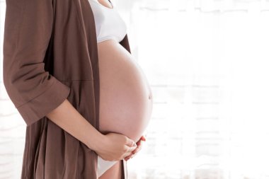 Evdeki pencerenin yanında duran güzel hamile kadın..