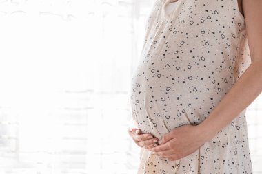 Evdeki pencerenin yanında duran güzel hamile kadın..