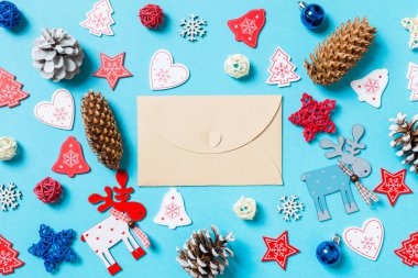 Yeni yıl oyuncakları ve mavi arka planda süslemelerle çevrili el sanatları zarfının üst görüntüsü. Noel zamanı konsepti.