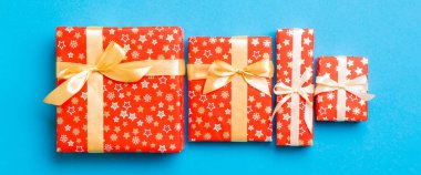 Noel 'i ya da diğer tatil hediyelerini mavi arka planda altın kurdeleyle kağıda sardım. Hediye kutusu, hediye dekorasyonu renkli masa, üst görünüm.