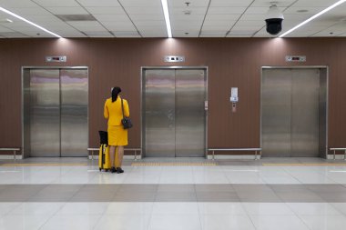 Hostes sarı üniforma ile onun uçuş programı kontrol ve Asansör kopya alanı ile terminal uluslararası havaalanında bekliyor.