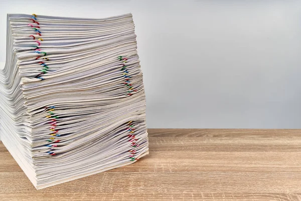 Stack of overload paperwork report of sale with colorful paper clip on wooden table with white background and copy space. Stack document is high as work hard. Business and finance concept success.
