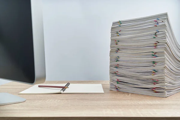 Lápiz en cuaderno con papeleo de sobrecarga y computadora en la mesa Fotos de stock libres de derechos