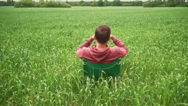 Un uomo si rilassa su una sedia in un grande campo verde — Video Stock