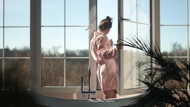Menina bebendo café na luz do sol da manhã na janela aberta — Vídeo de Stock