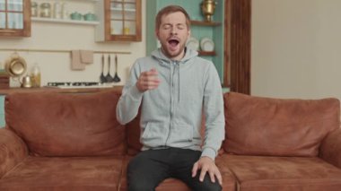 Oturma odasında esneyen yorgun genç adam..