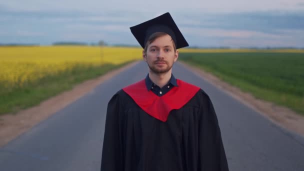 Satisfied graduate shows diploma standing on the road — Stock Video