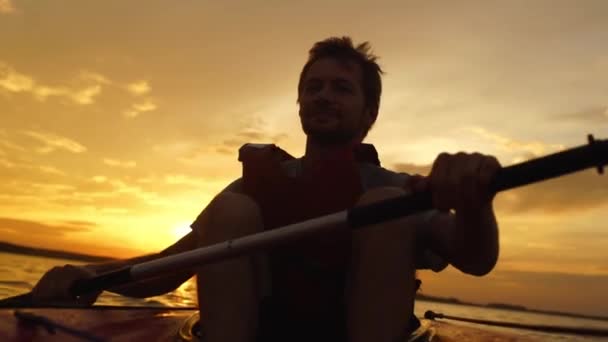 Силуэт человека, катающегося на каяке на озере на закате. Отдых на природе — стоковое видео