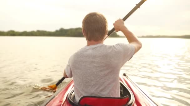 Man paddlar kajak på sjön vid solnedgången. Avslappnande i naturen — Stockvideo