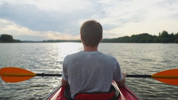 Genç bir adam teknede huzur içinde oturur ve doğada yalnızlığın tadını çıkarır. — Stok video