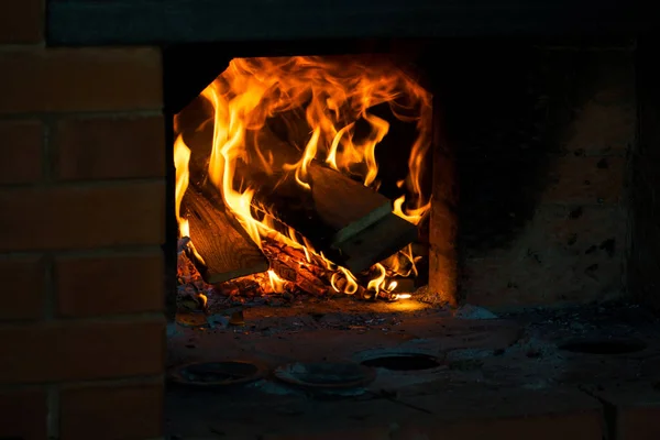 Crest of flame on burning wood in fireplace.