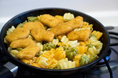 Bir tavada tavuk nuggets ile makarna. Kızarmış tavuk Nuggets.