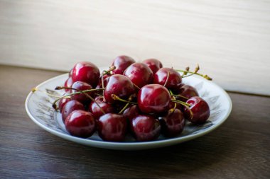 Ahşap bir masa üzerinde bir plaka üzerinde taze lezzetli kiraz meyve