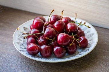 Ahşap bir masa üzerinde bir plaka üzerinde taze lezzetli kiraz meyve
