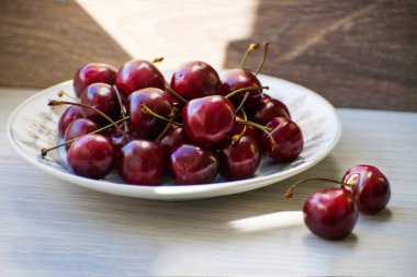Ahşap bir masa üzerinde bir plaka üzerinde taze lezzetli kiraz meyve