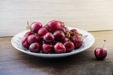 Ahşap bir masa üzerinde bir plaka üzerinde taze lezzetli kiraz meyve