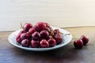 Ahşap bir masa üzerinde bir plaka üzerinde taze lezzetli kiraz meyve
