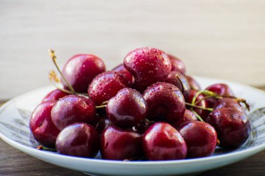 Ahşap bir masa üzerinde bir plaka üzerinde taze lezzetli kiraz meyve