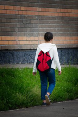Kız okula siyah sırt çantası ile. Arkadan görünüm.