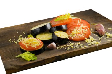 Doğranmış patlıcan ve domates. Domates, patlıcan, peynirler, sarımsak ve kereviz ahşap oyun tahtası.