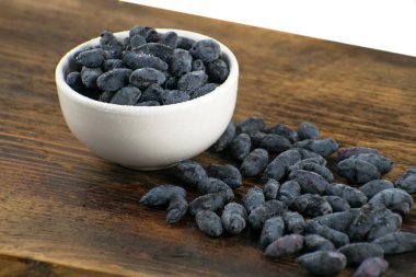 Ahşap bir gemide bir seramik kase taze olgun Hanımeli çilek. Sağlıklı kahvaltı.