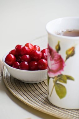 Beyaz bir kase ve bir tabloda çay kırmızı olgun kiraz