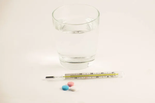 Pohár Víz Tabletták Hőmérő Fehér Háttér Üveg Higany Hőmérő Magas — Stock Fotó