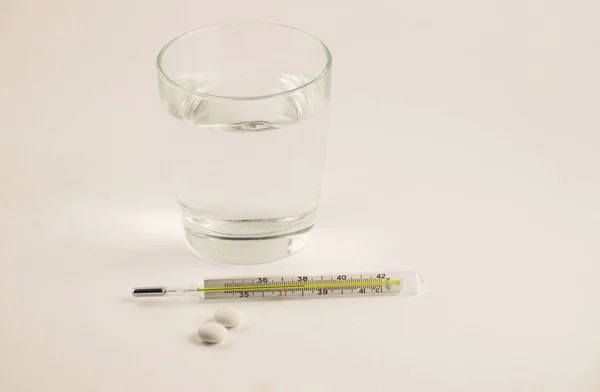 Pohár Víz Tabletták Hőmérő Fehér Háttér Üveg Higany Hőmérő Magas — Stock Fotó