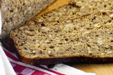 Kesme tahtasında dilimlenmiş çavdar ekmeği. Tohumlu tam tahıllı çavdar ekmeği..
