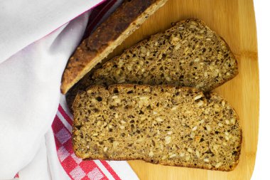 Kesme tahtasında dilimlenmiş çavdar ekmeği. Tohumlu tam tahıllı çavdar ekmeği..