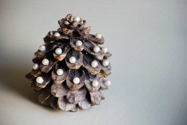 Çam kozalağı bir yılbaşı ağacı şeklinde. Çam kozalağı inciler ile dekore edilmiş.